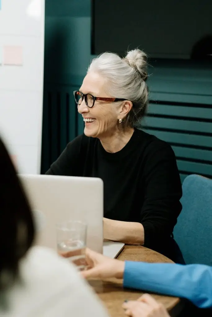 Smiling senior businesswoman leading a diverse team meeting in an office.